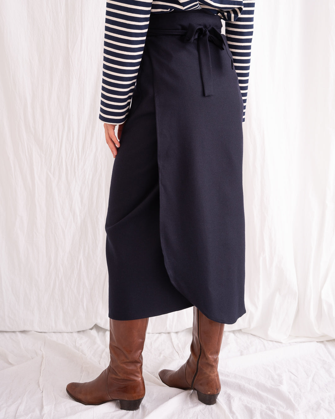 Model is wearing the Wrapped Wool Skirt by Les Vacances d’Irina, a mid-length dark-navy handmade wool skirt with fluid wrap design, available at House of Woven Stories.