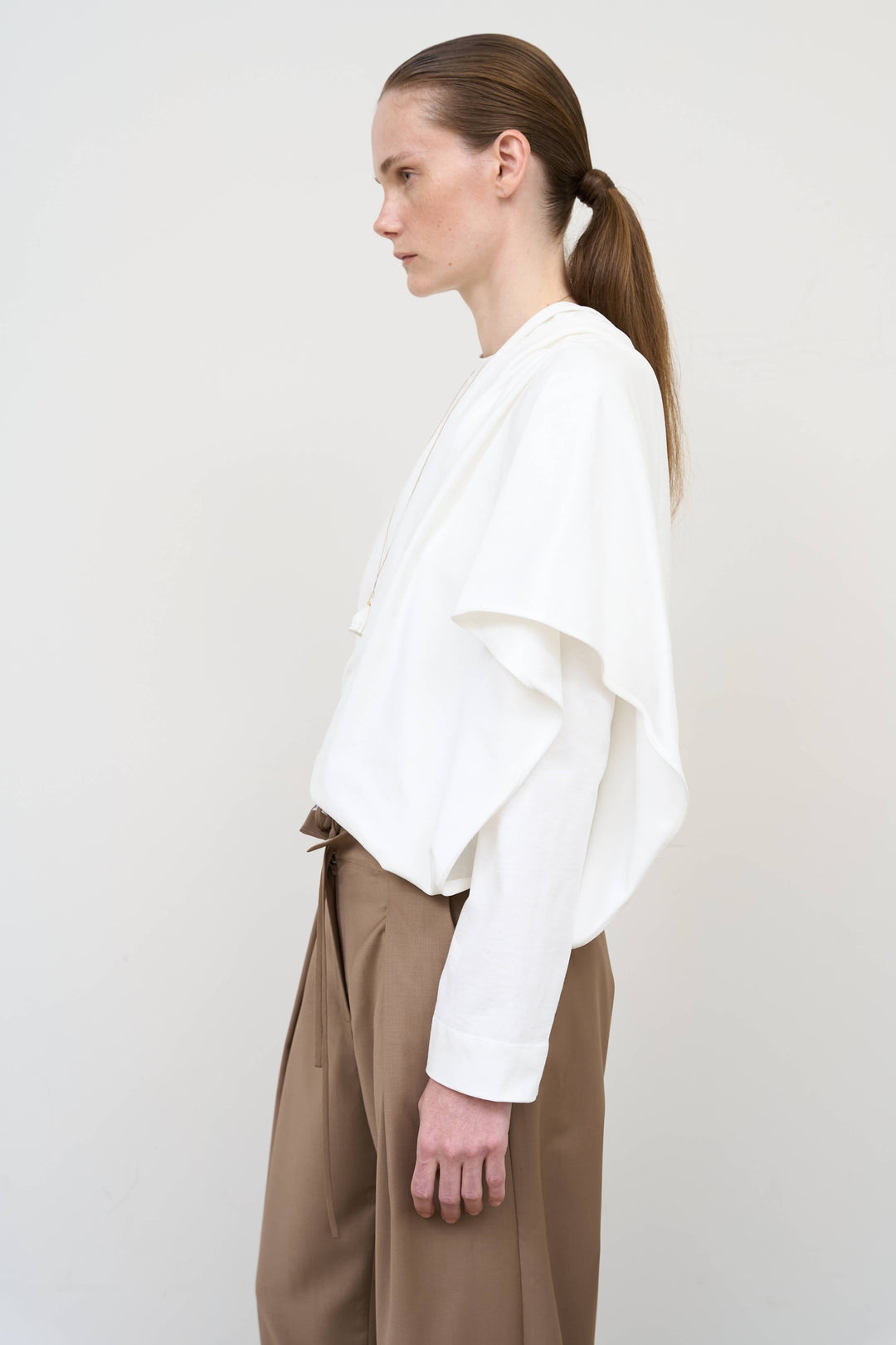 Model is wearing Litkovska asymmetric white cotton longsleeve showcasing elongated silhouette and contemporary designer womenswear at House of Nomad Stories