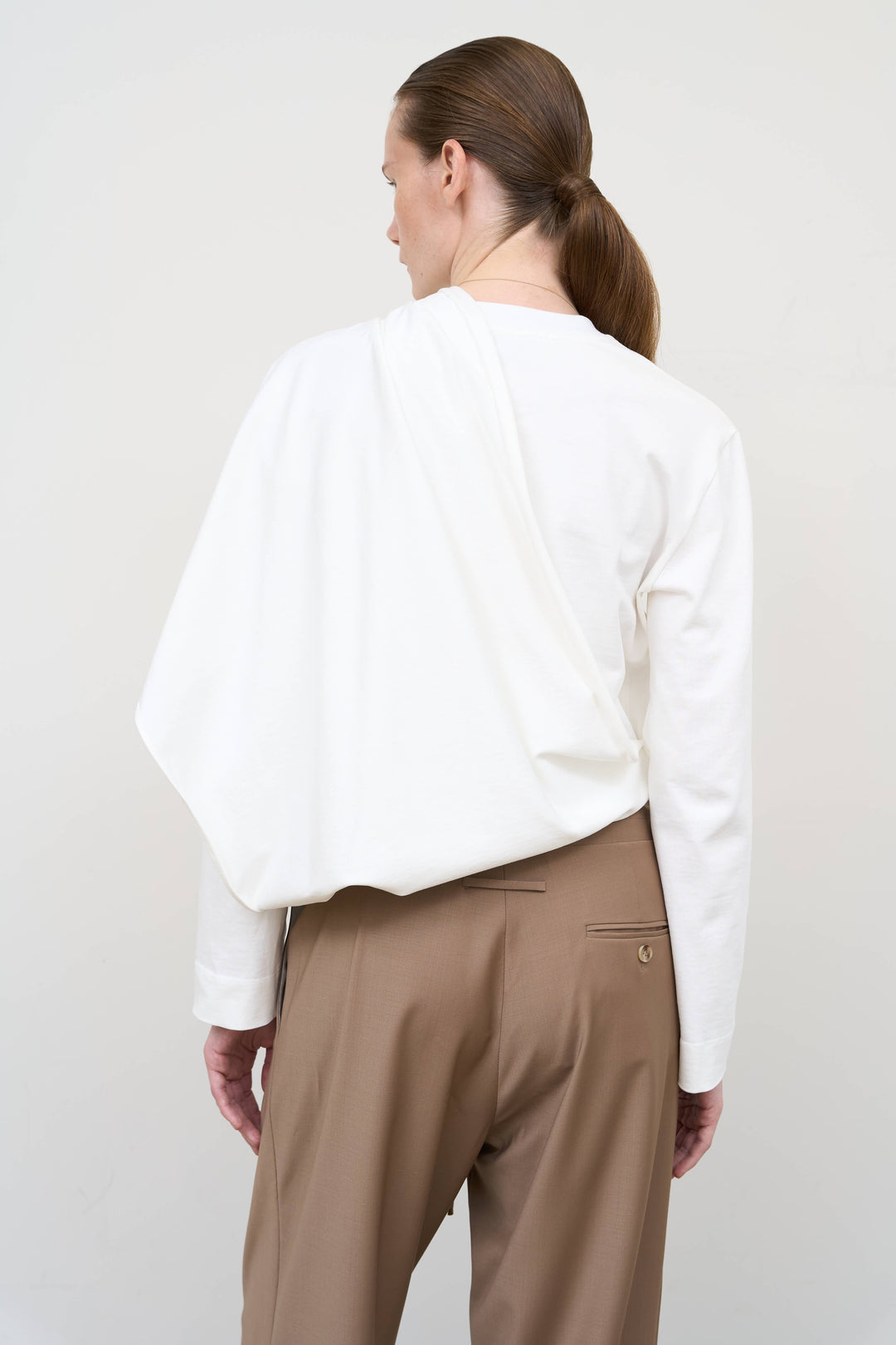 Model is wearing Litkovska asymmetric white cotton longsleeve showcasing elongated silhouette and contemporary designer womenswear at House of Nomad Stories