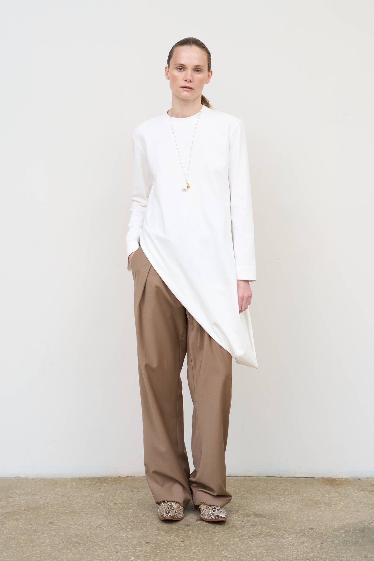Model is wearing Litkovska asymmetric white cotton longsleeve showcasing elongated silhouette and contemporary designer womenswear at House of Nomad Stories