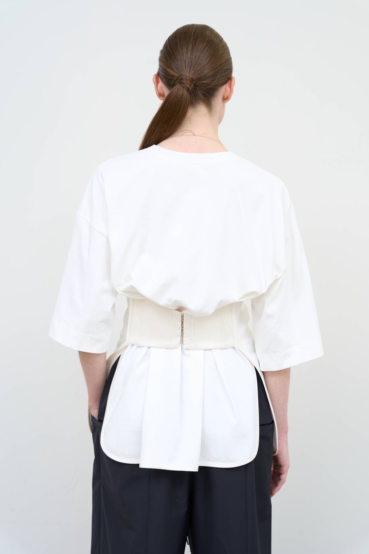 Model is wearing Litkovska corset white T-shirt showcasing tailored waist detail and contemporary designer womenswear at House of Nomad Stories