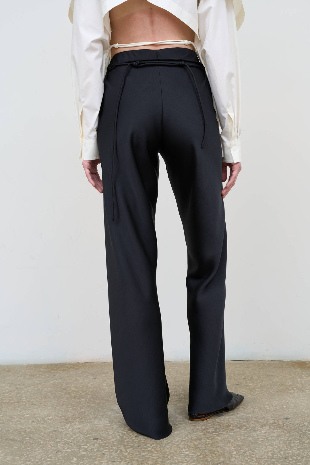 Model is wearing Litkovska black straight-leg trousers with high-rise waist, refined tailoring and minimalist styling