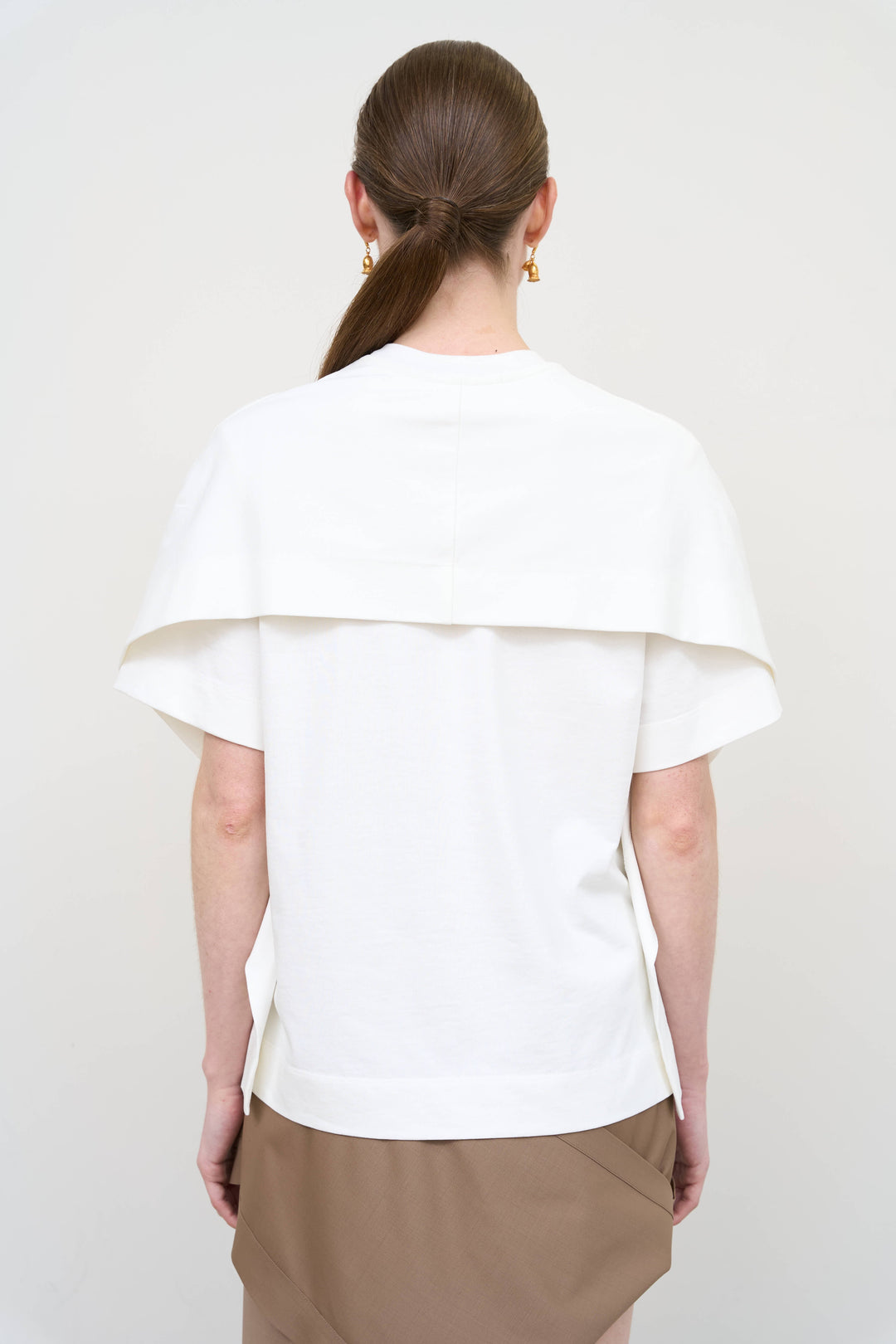 Model is wearing a white overlay cotton T-shirt by Litkovska with relaxed fit and layered architectural design, modern designer women’s T-shirt available at House of Woven Stories
