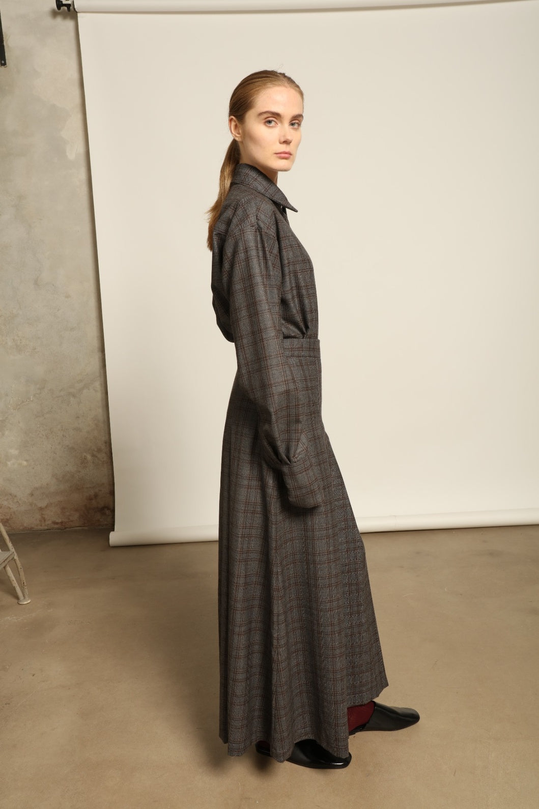 Model is wearing the Londra Brown Checked Skirt by House of Nomad Stories, ankle-length with fine pleats and brown checked pattern, combining timeless tailoring with contemporary elegance and quality craftsmanship.