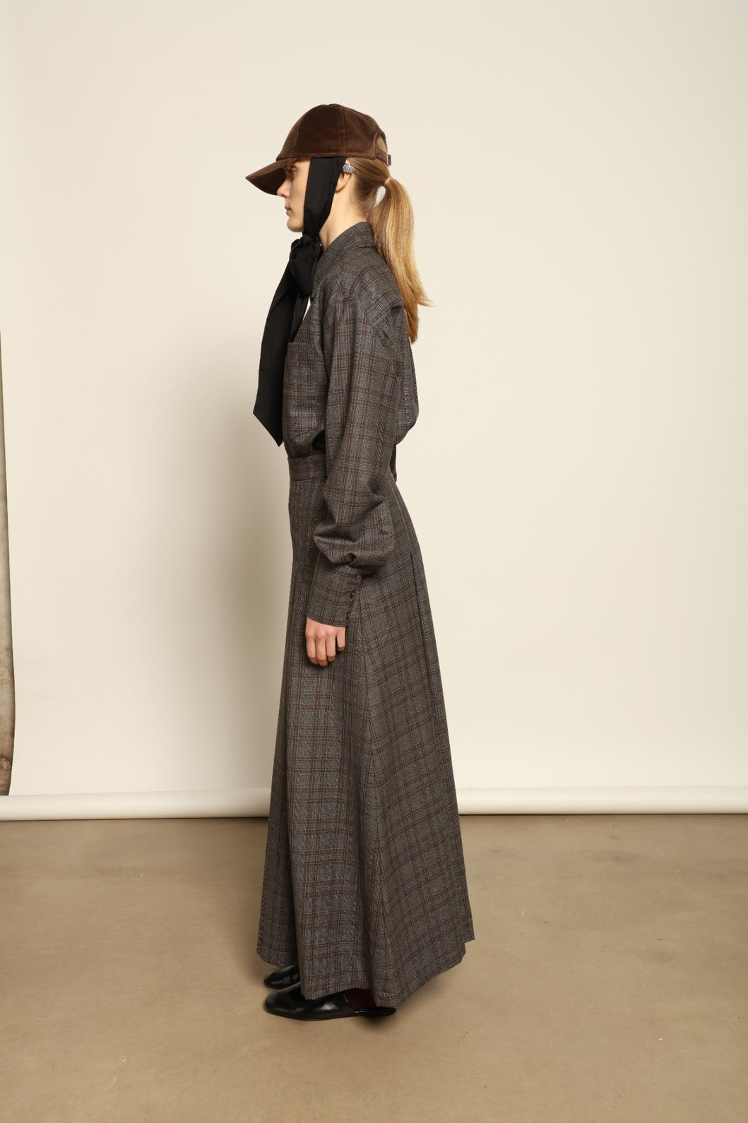 Model is wearing the Londra Brown Checked Skirt by House of Nomad Stories, ankle-length with fine pleats and brown checked pattern, combining timeless tailoring with contemporary elegance and quality craftsmanship.