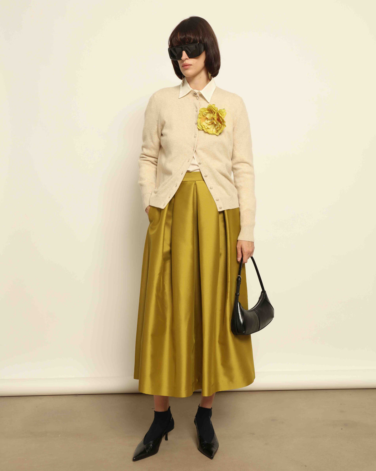 Model is wearing Duchesse Oliva Skirt by Lunatica Milano available at House of Nomad Stories. Pleated maxi skirt in a luxurious soft-blend fabric. Elegant, feminine, and handmade in Italy.