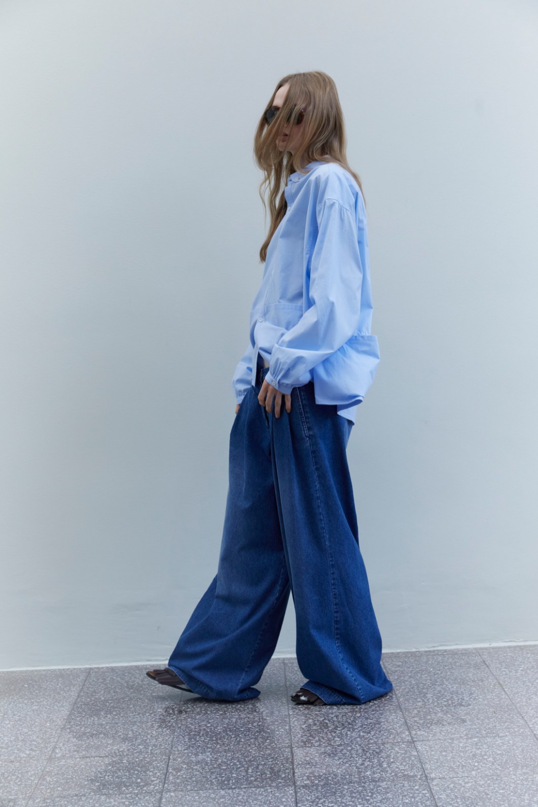 Side view of the Katherine Washed Blue Denim Pant by Maison Jejia, highlighting its fluid volume, relaxed wide leg and structured cotton denim.