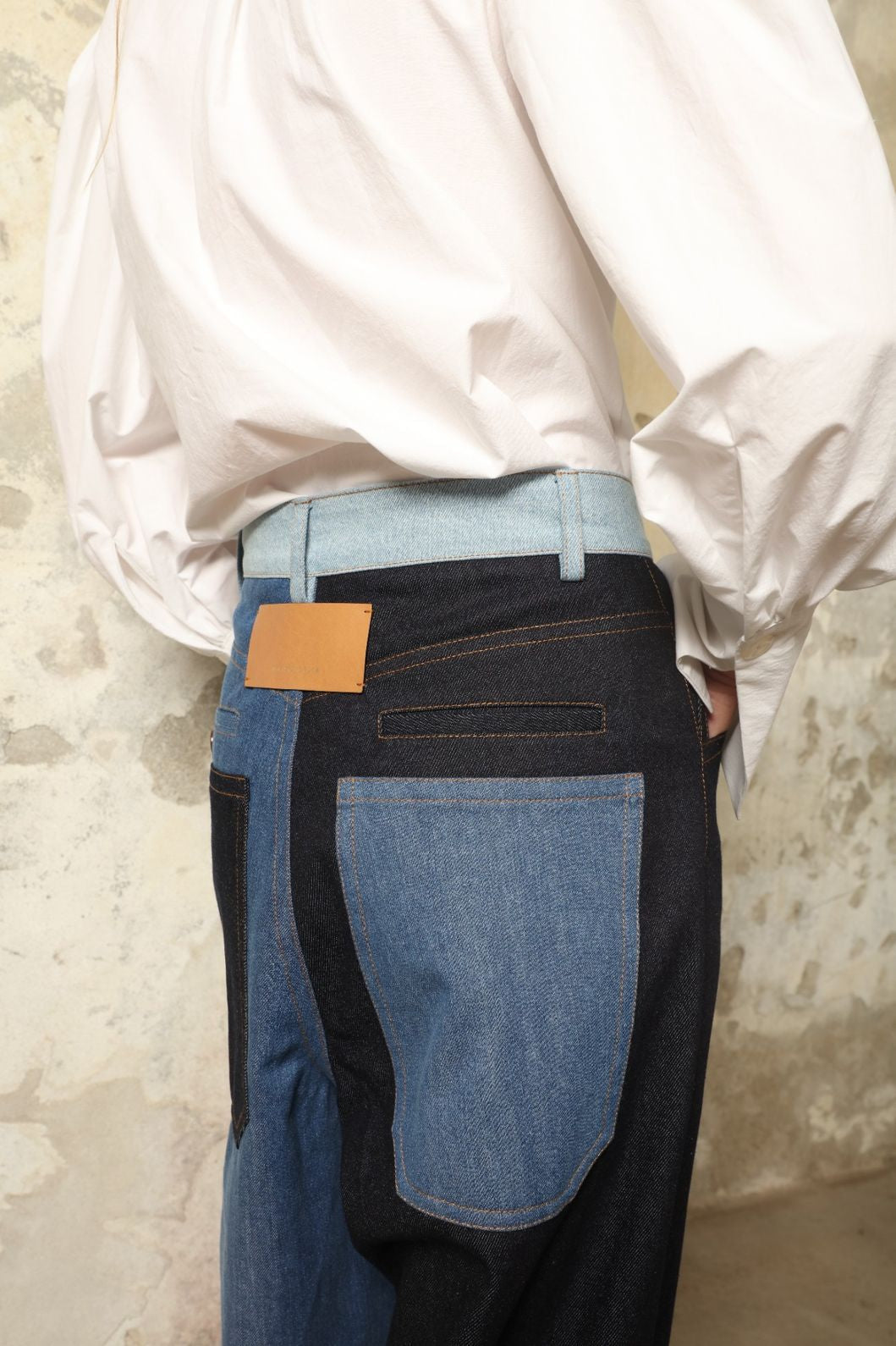 Model is wearing the Carla Denim Patchwork Pant by Maison Jejia, tailored denim trousers crafted from mixed-wash patches with a relaxed structured silhouette and fine stitching, curated in the House of Nomad Stories selection