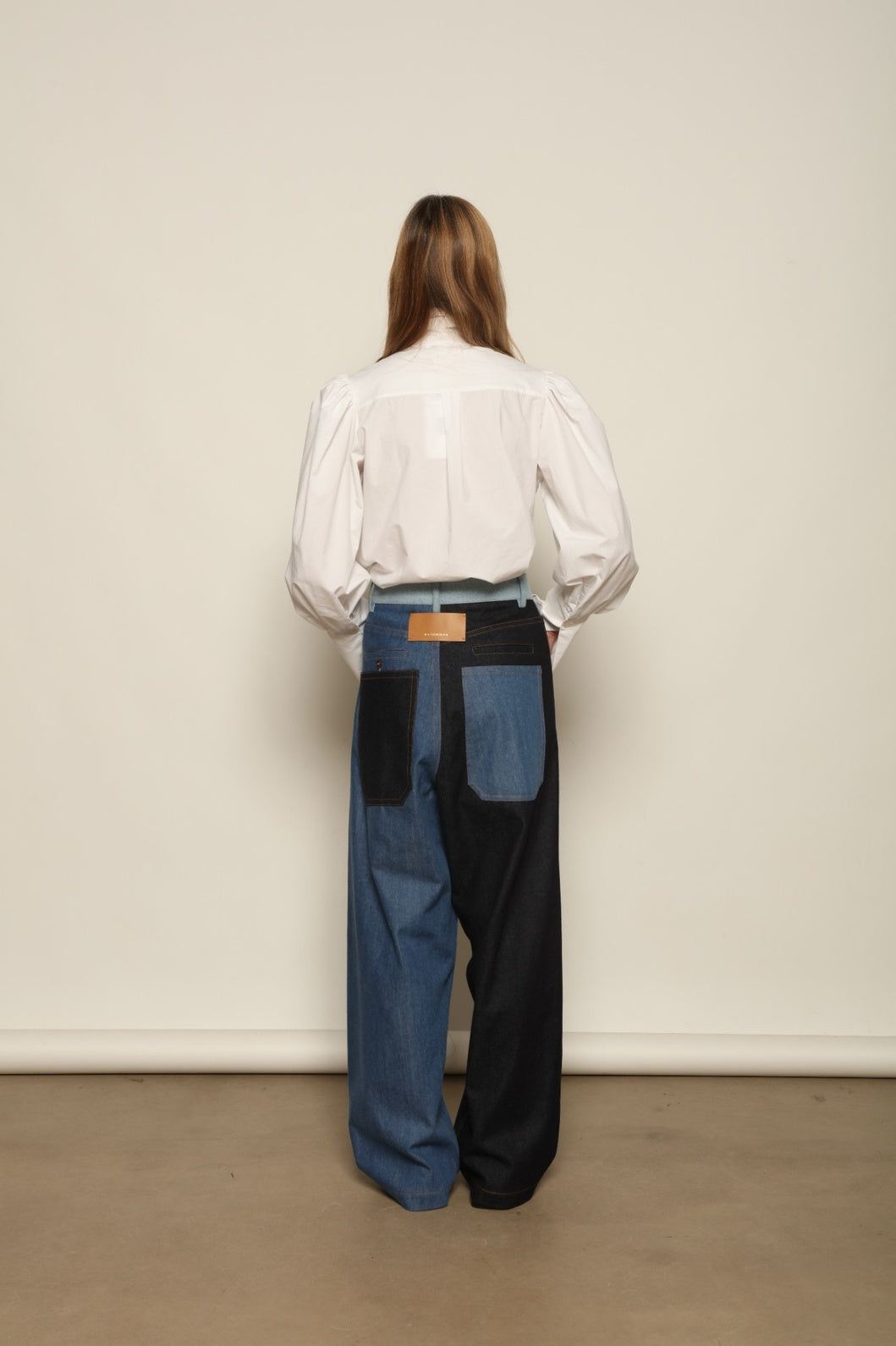 Model is wearing the Carla Denim Patchwork Pant by Maison Jejia, tailored denim trousers crafted from mixed-wash patches with a relaxed structured silhouette and fine stitching, curated in the House of Nomad Stories selection