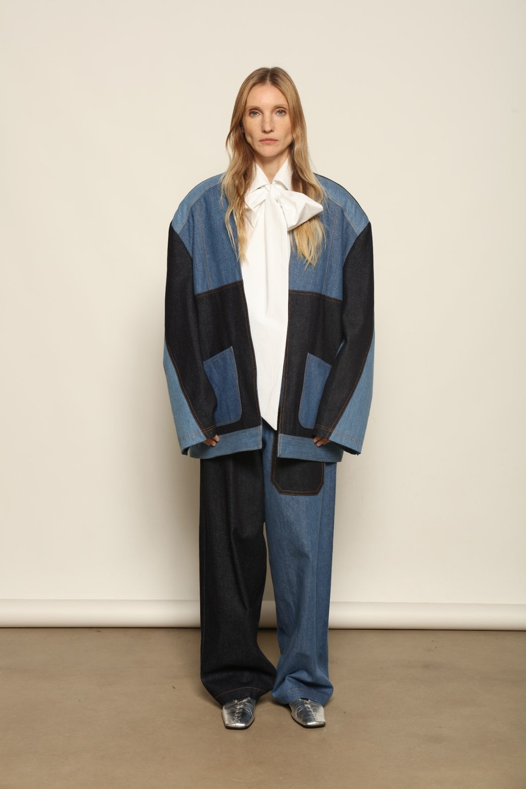 Model is wearing the Jonathan Denim Patchwork Blazer by Maison Jejia, an artisanal tailored blazer made from mixed-wash denim panels with sculpted shoulders and a relaxed sharp silhouette, curated in the House of Nomad Stories selection