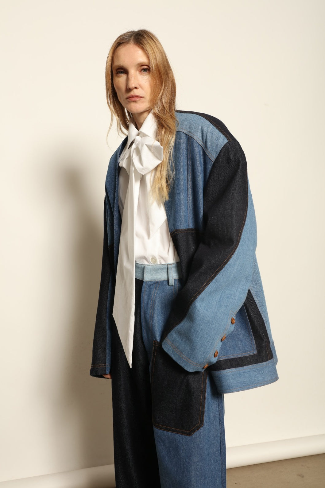 Model is wearing the Jonathan Denim Patchwork Blazer by Maison Jejia, an artisanal tailored blazer made from mixed-wash denim panels with sculpted shoulders and a relaxed sharp silhouette, curated in the House of Nomad Stories selection