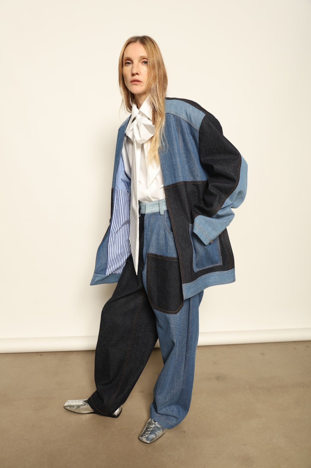 Model is wearing the Jonathan Denim Patchwork Blazer by Maison Jejia, an artisanal tailored blazer made from mixed-wash denim panels with sculpted shoulders and a relaxed sharp silhouette, curated in the House of Nomad Stories selection