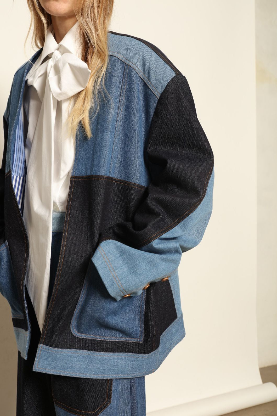 Model is wearing the Jonathan Denim Patchwork Blazer by Maison Jejia, an artisanal tailored blazer made from mixed-wash denim panels with sculpted shoulders and a relaxed sharp silhouette, curated in the House of Nomad Stories selection