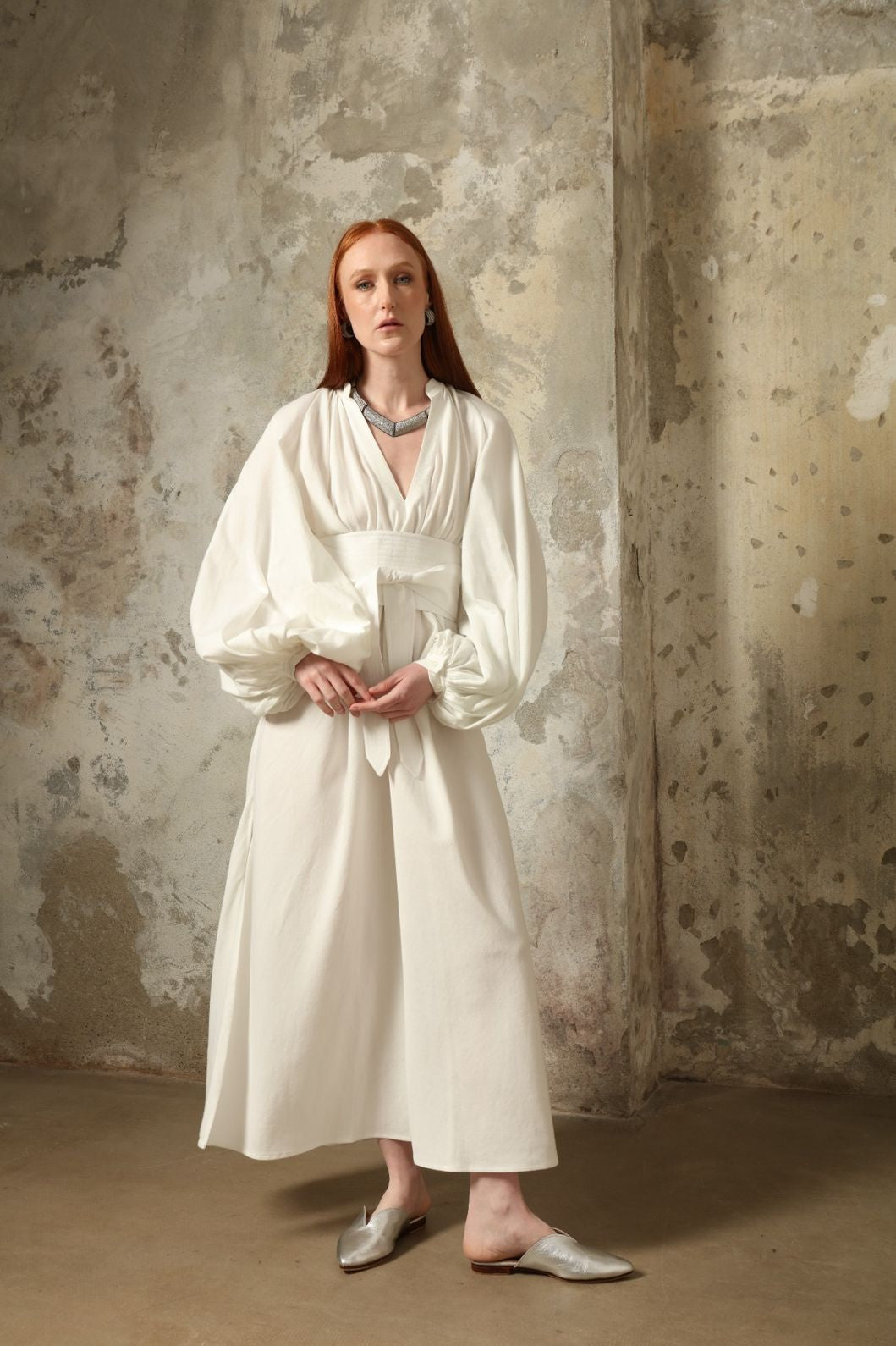 Touareg Dress by Marrakshi Life in crisp handwoven white cotton, featuring a V-neckline, long balloon sleeves with buttoned cuffs, side slits and a removable belt.