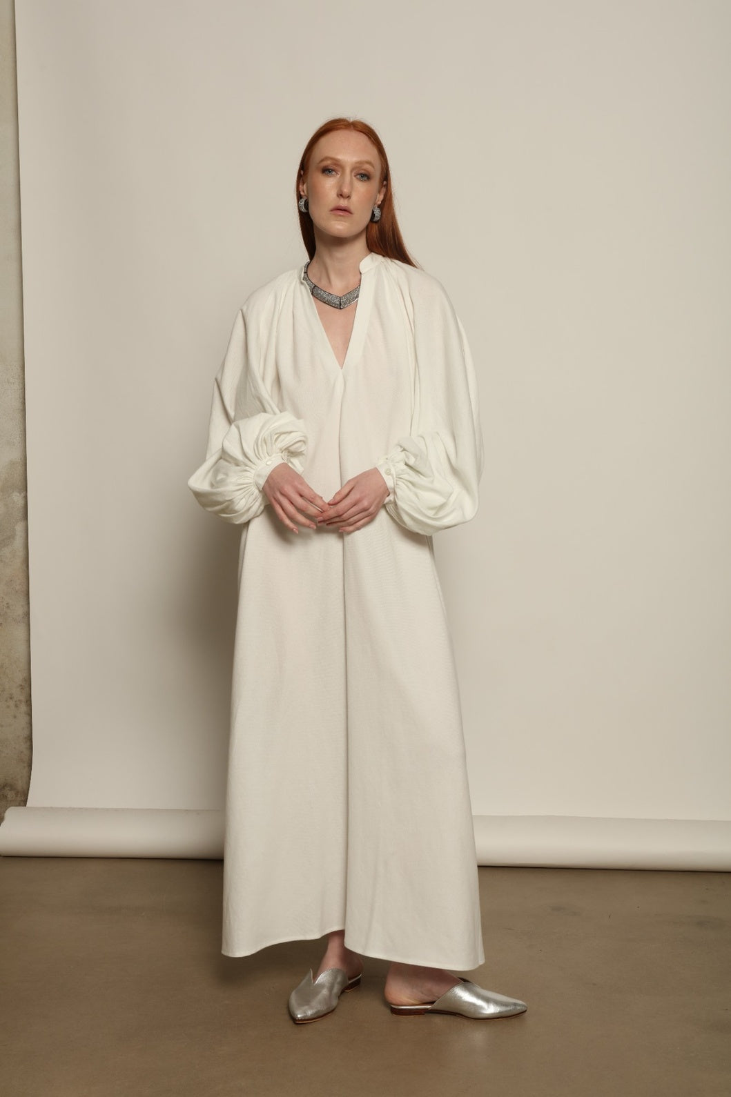 Touareg Dress by Marrakshi Life in crisp handwoven white cotton, featuring a V-neckline, long balloon sleeves with buttoned cuffs, side slits and a removable belt.