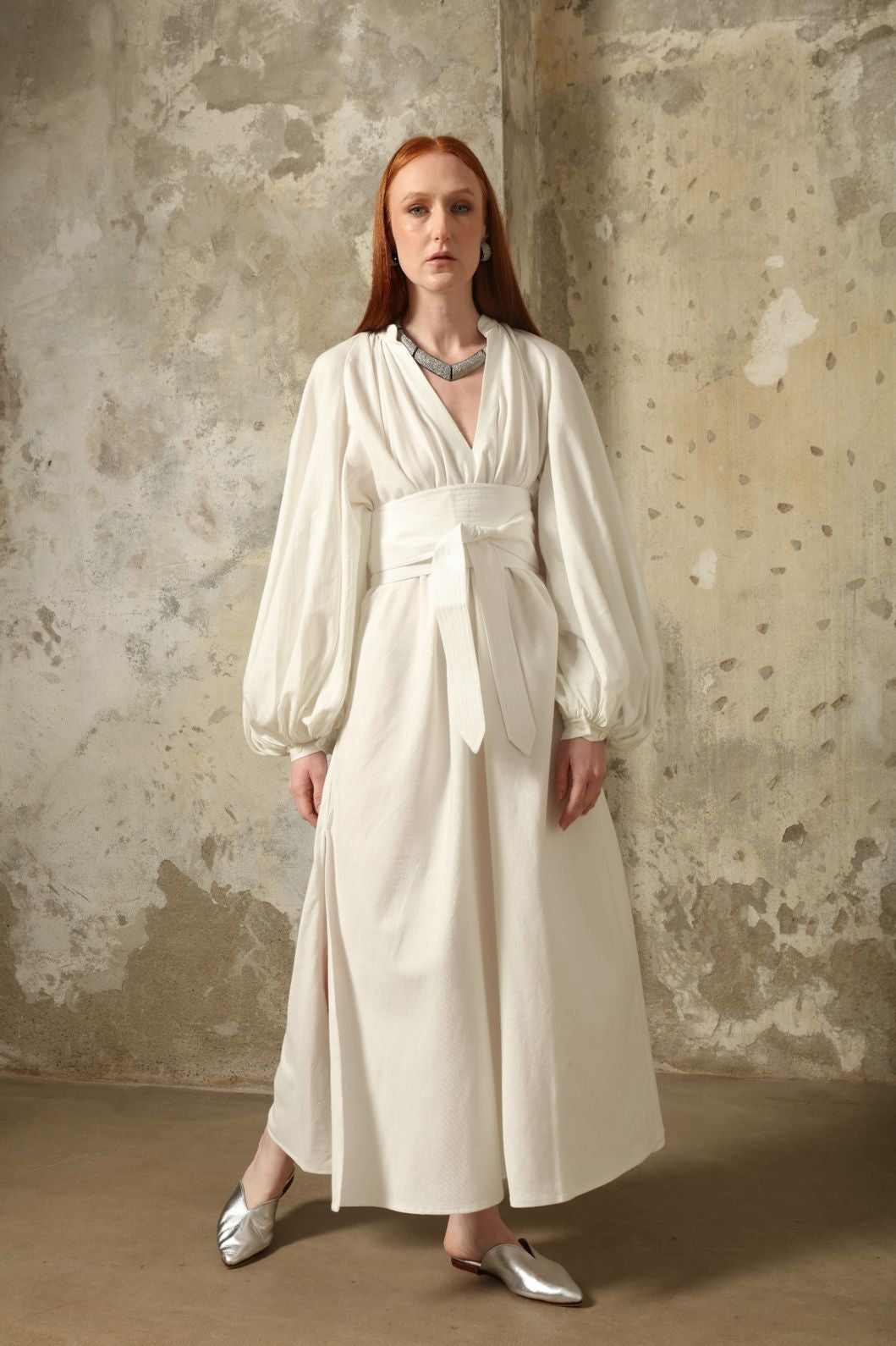 Touareg Dress by Marrakshi Life in crisp handwoven white cotton, featuring a V-neckline, long balloon sleeves with buttoned cuffs, side slits and a removable belt.
