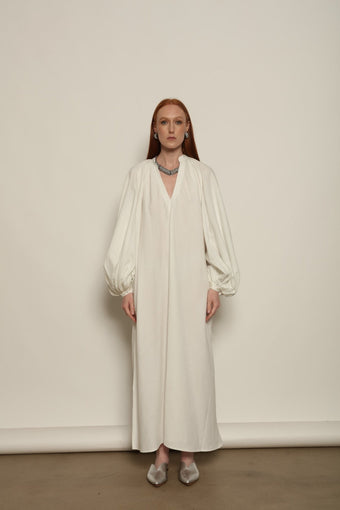 Touareg Dress by Marrakshi Life in crisp handwoven white cotton, featuring a V-neckline, long balloon sleeves with buttoned cuffs, side slits and a removable belt.