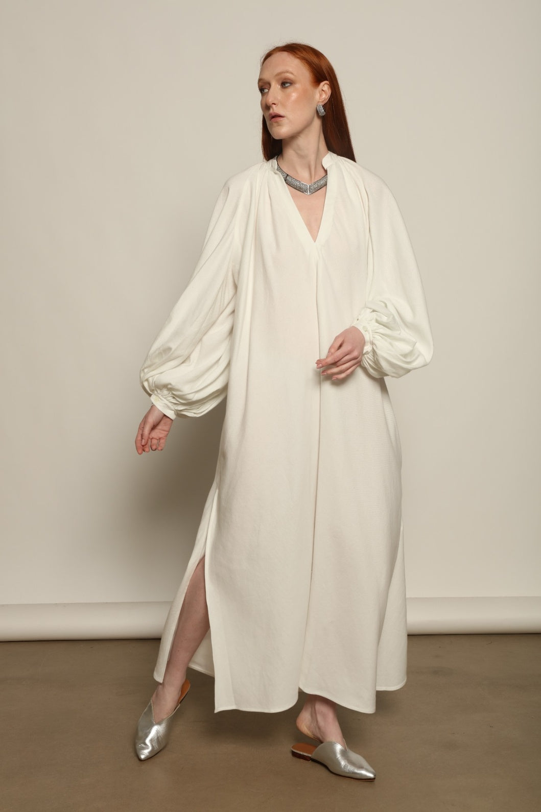 Touareg Dress by Marrakshi Life in crisp handwoven white cotton, featuring a V-neckline, long balloon sleeves with buttoned cuffs, side slits and a removable belt.