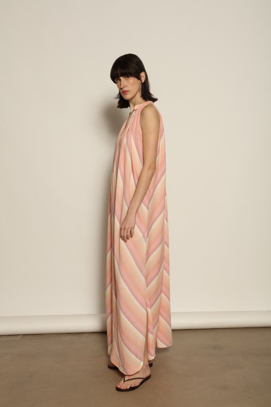 Model is wearing Marrakshi Life halter maxi dress in multicolor striped handwoven cotton, lightweight breathable sleeveless V-neck dress with flowy silhouette and side slits from the curated selection of House of Woven Stories