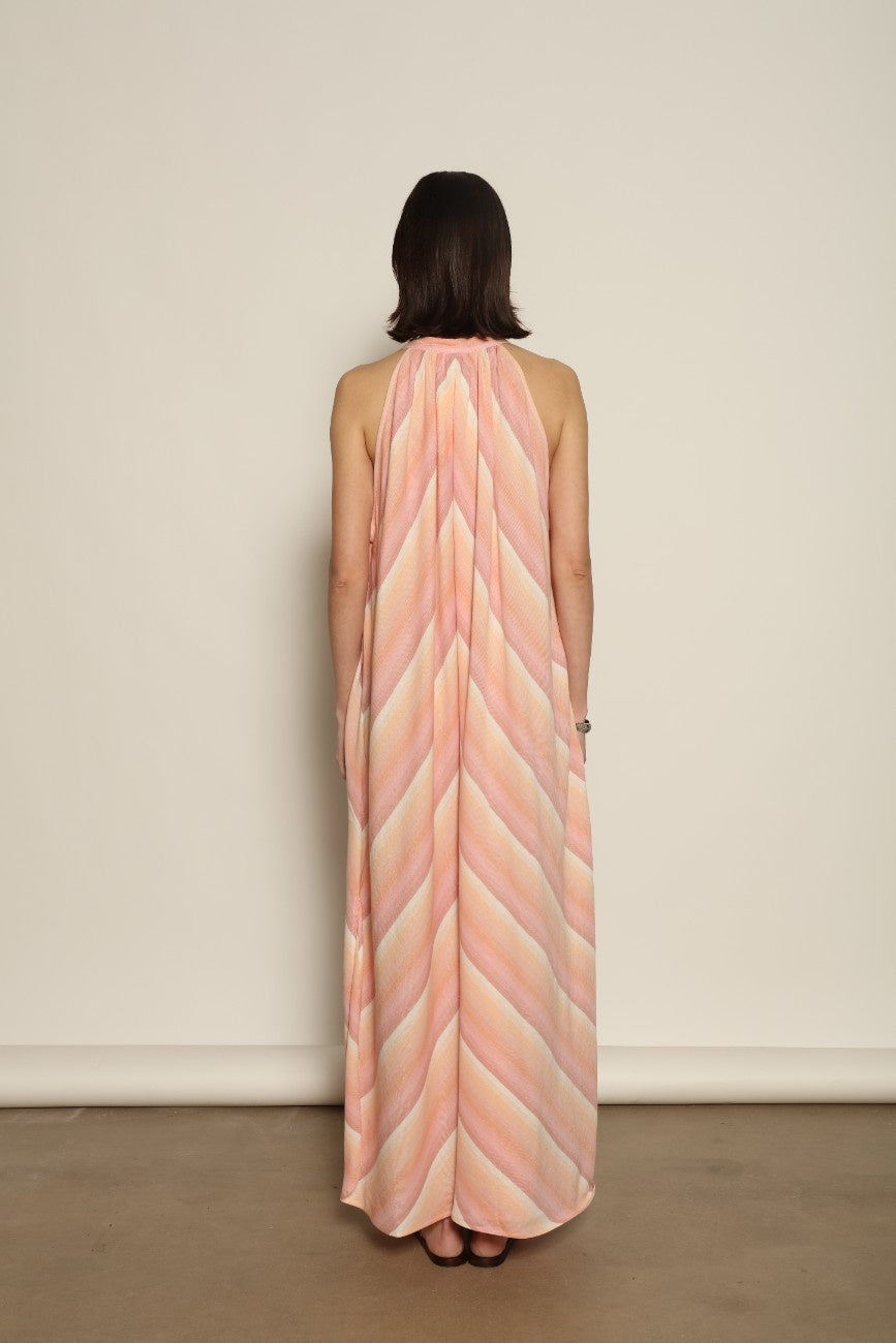Model is wearing Marrakshi Life halter maxi dress in multicolor striped handwoven cotton, lightweight breathable sleeveless V-neck dress with flowy silhouette and side slits from the curated selection of House of Woven Stories