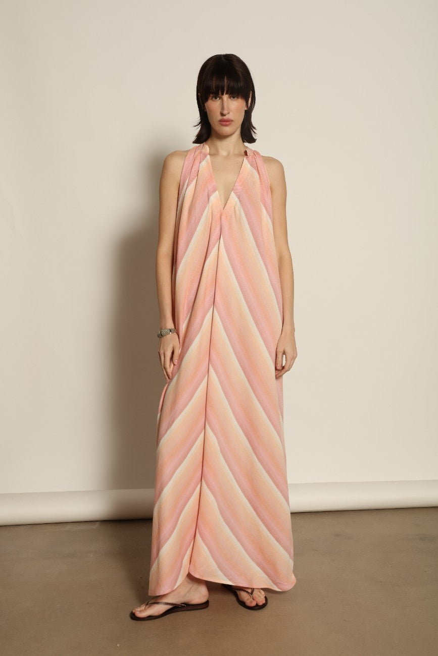 Model is wearing Marrakshi Life halter maxi dress in multicolor striped handwoven cotton, lightweight breathable sleeveless V-neck dress with flowy silhouette and side slits from the curated selection of House of Woven Stories