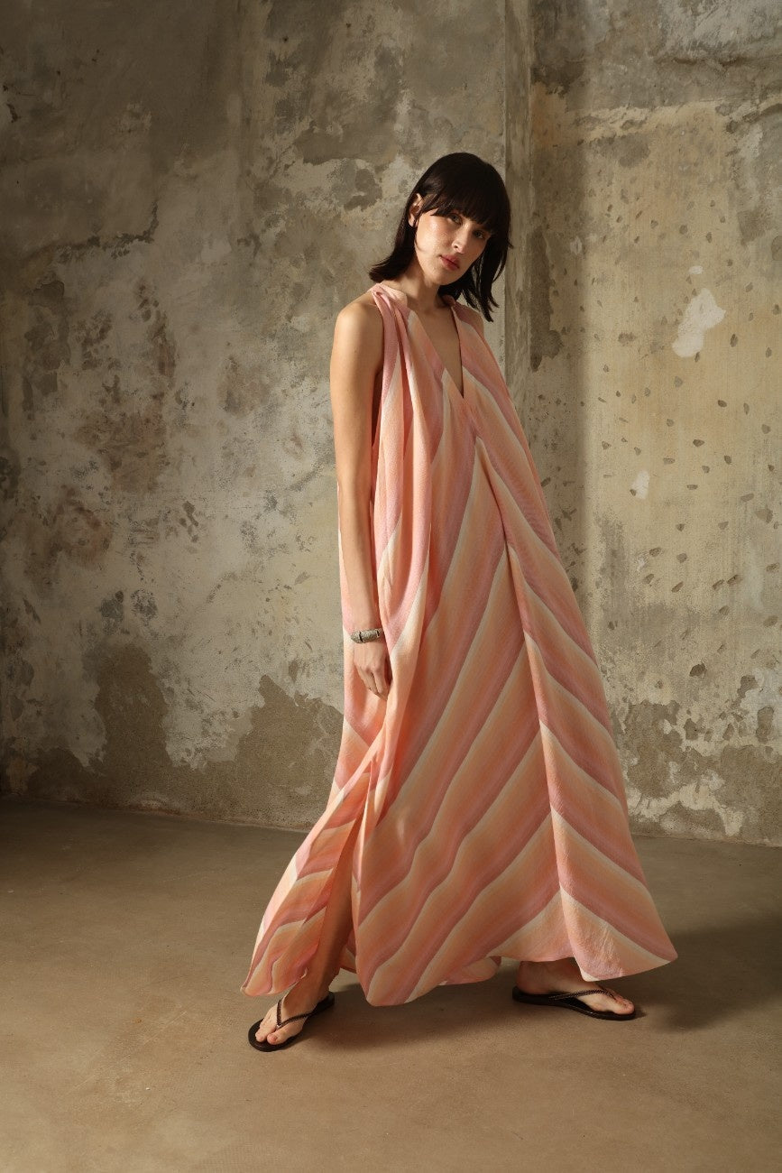 Model is wearing Marrakshi Life halter maxi dress in multicolor striped handwoven cotton, lightweight breathable sleeveless V-neck dress with flowy silhouette and side slits from the curated selection of House of Woven Stories