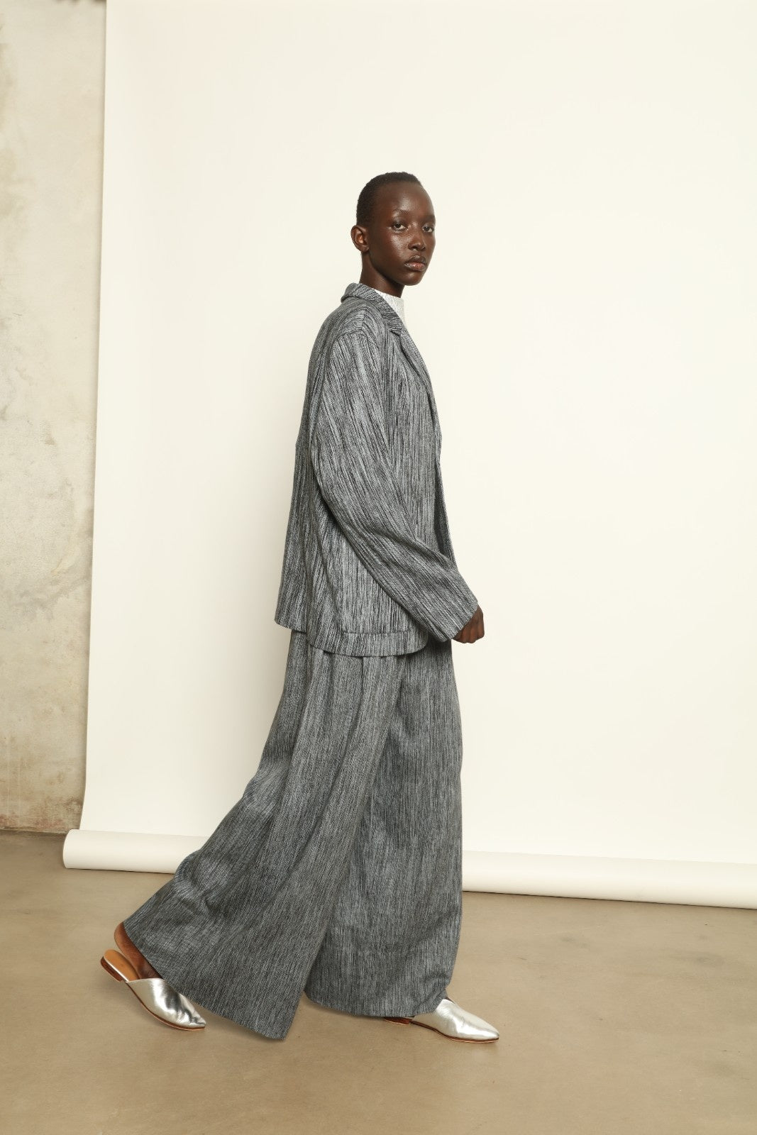 Model is wearing the Mid Rise Grey Chambray Pant by Marrakshi Life, part of House of Nomad Stories collection, handwoven cotton wide-leg pants with relaxed fit and subtle textured chambray