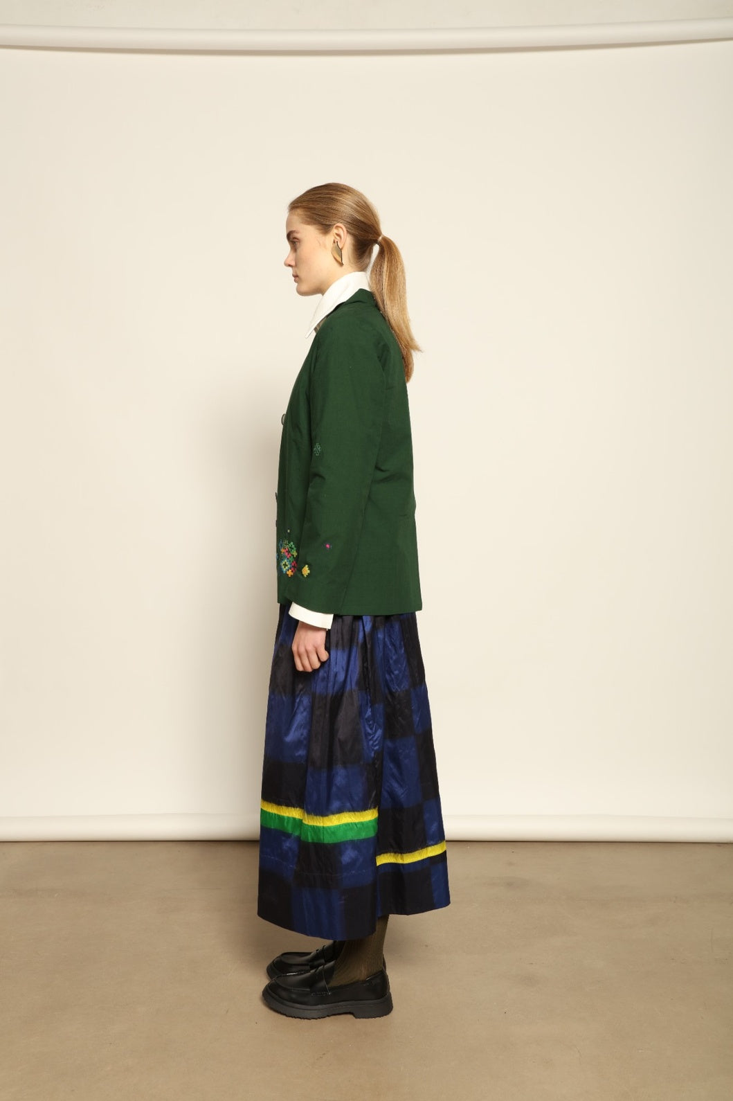 Model is wearing the Miraj 106 Cotton and Silk Skirt by Injiri, handcrafted in India with a blue check base and vibrant green and yellow rectangular motifs, blending heritage craftsmanship with bold contemporary design.
