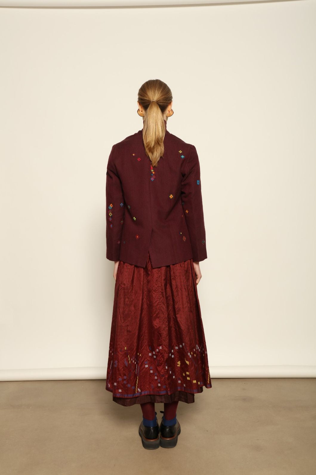 Model wearing the Miraj 195 Jacket by Injiri, handwoven from maroon wool and silk with intricate Jamdani motifs, curated by House of Nomad Stories.