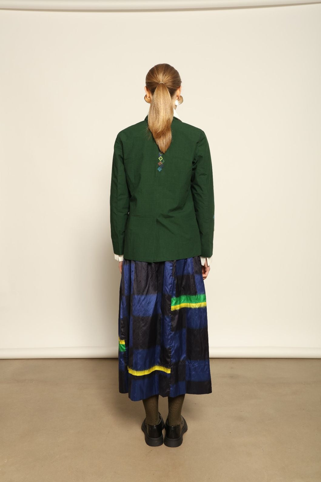 Model is wearing the Miraj 65 Cotton and Silk Jacket by Injiri, handwoven in deep green cotton and silk with geometric Jamdani motifs, blending Indian craftsmanship with contemporary elegance.