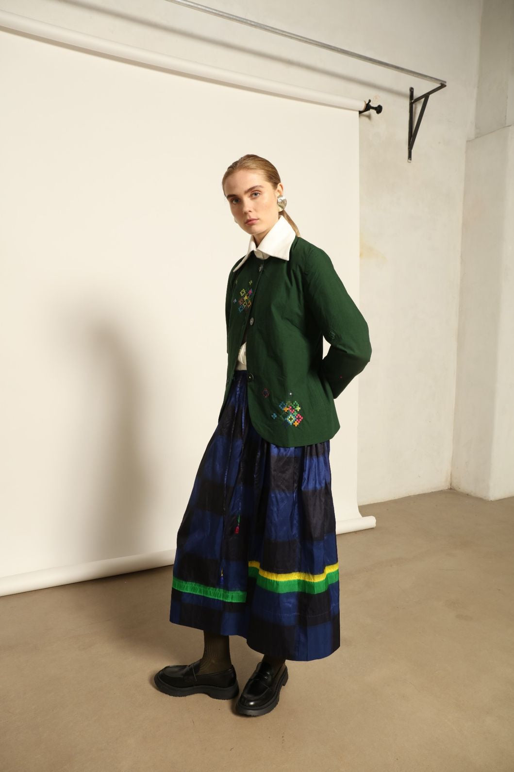 Model is wearing the Miraj 65 Cotton and Silk Jacket by Injiri, handwoven in deep green cotton and silk with geometric Jamdani motifs, blending Indian craftsmanship with contemporary elegance.