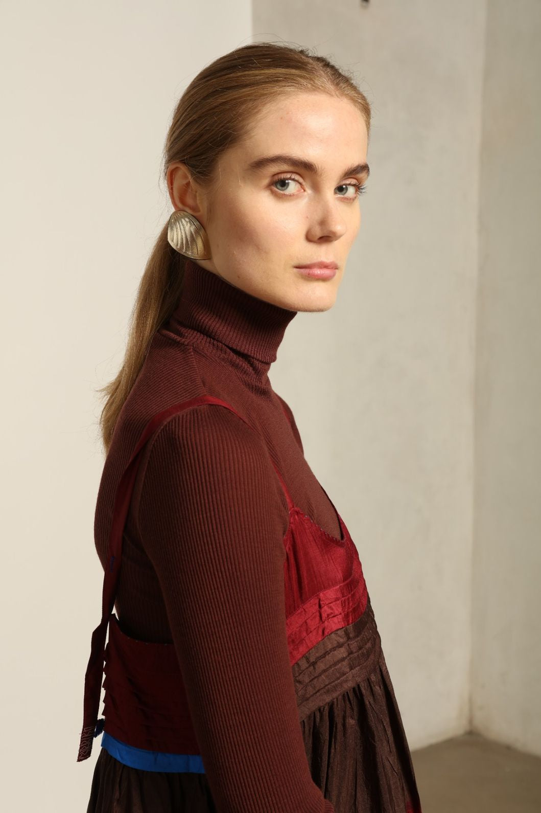 Model is wearing the Miraj 95 Silk and Cotton Slip Dress by Injiri, crafted in red and brown cotton with silk accents and a bold blue border, combining lightness, color, and refined craftsmanship.