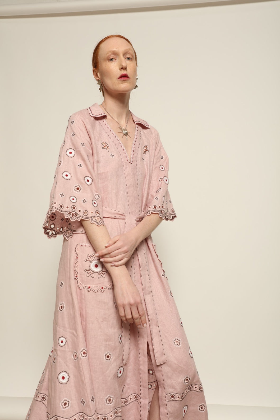 Model is wearing the My Sleeping Gypsy Glass House Long Dress in powder pink linen with Zbiranka pleating, Richelieu embroidery, and 24-carat bead accents, from the House of Nomad Stories selection.