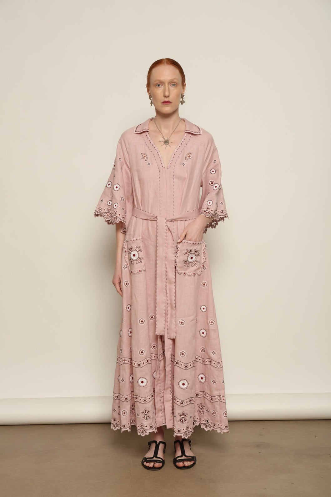 Model is wearing the My Sleeping Gypsy Glass House Long Dress in powder pink linen with Zbiranka pleating, Richelieu embroidery, and 24-carat bead accents, from the House of Nomad Stories selection.