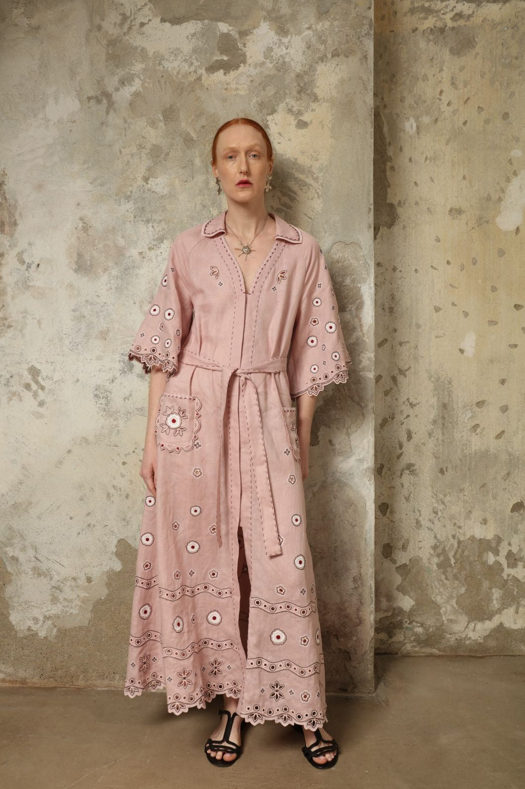 Model is wearing the My Sleeping Gypsy Glass House Long Dress in powder pink linen with Zbiranka pleating, Richelieu embroidery, and 24-carat bead accents, from the House of Nomad Stories selection.