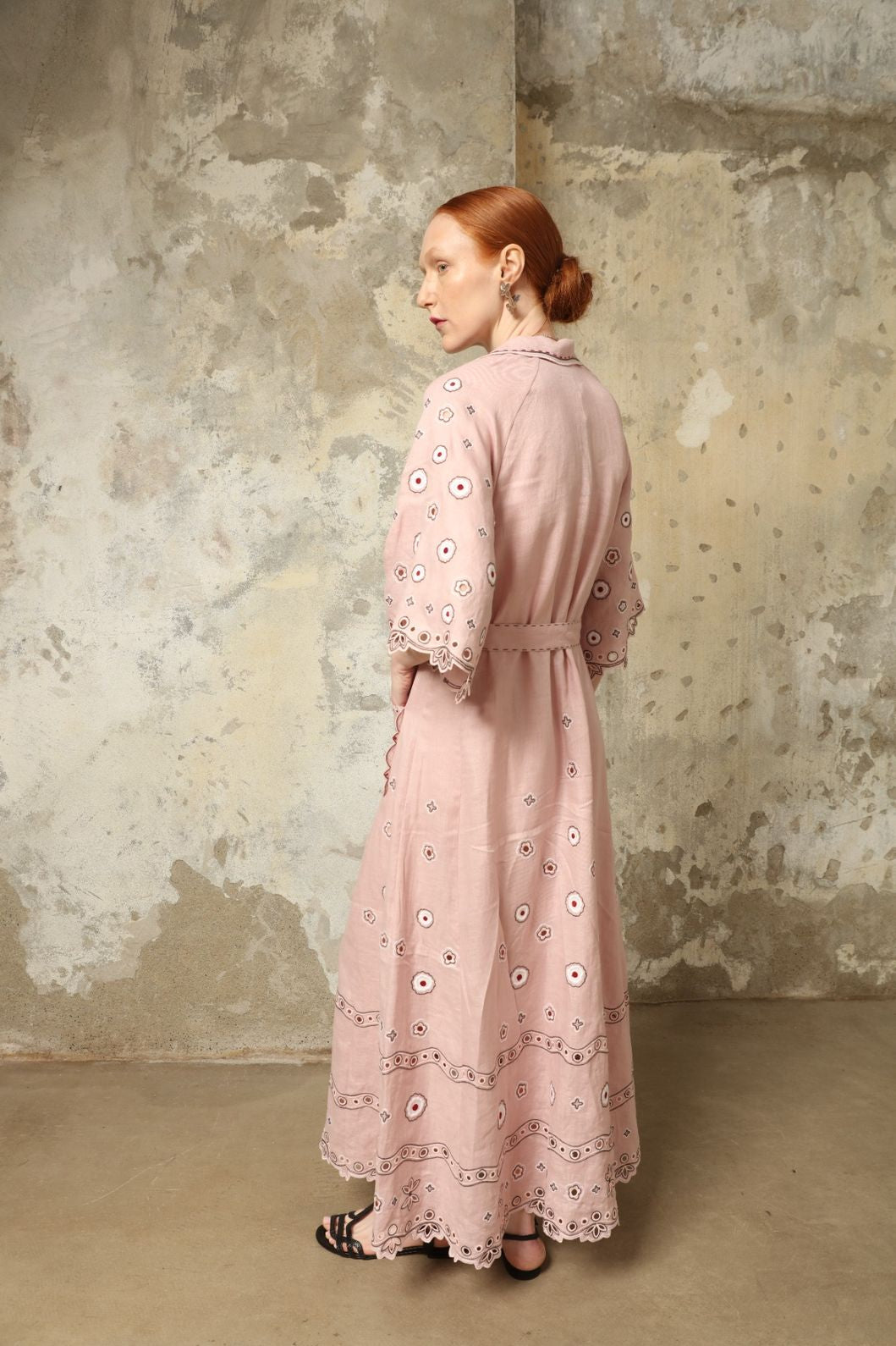 Model is wearing the My Sleeping Gypsy Glass House Long Dress in powder pink linen with Zbiranka pleating, Richelieu embroidery, and 24-carat bead accents, from the House of Nomad Stories selection.