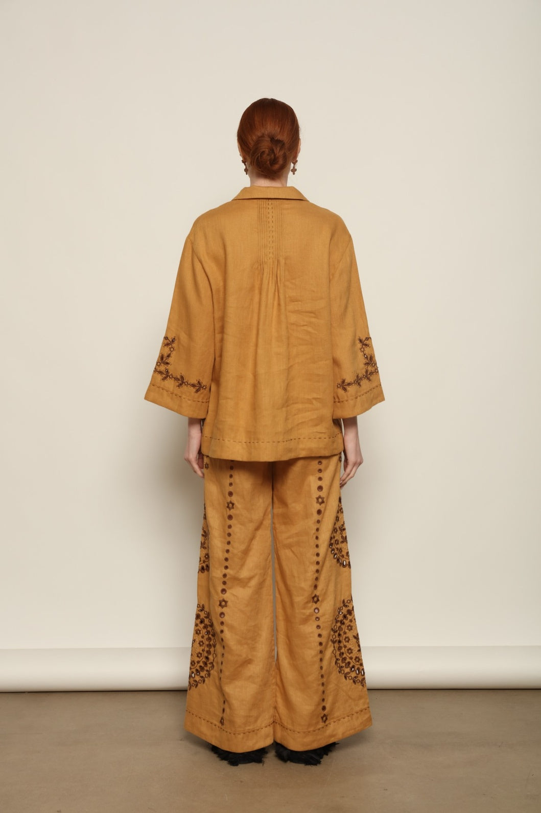 Model is wearing the My Sleeping Gypsy Sarah Pants, high-waisted 100% linen trousers with handmade lace, tonal embroidery, and 24-carat bead accents, from the House of Nomad Stories selection.