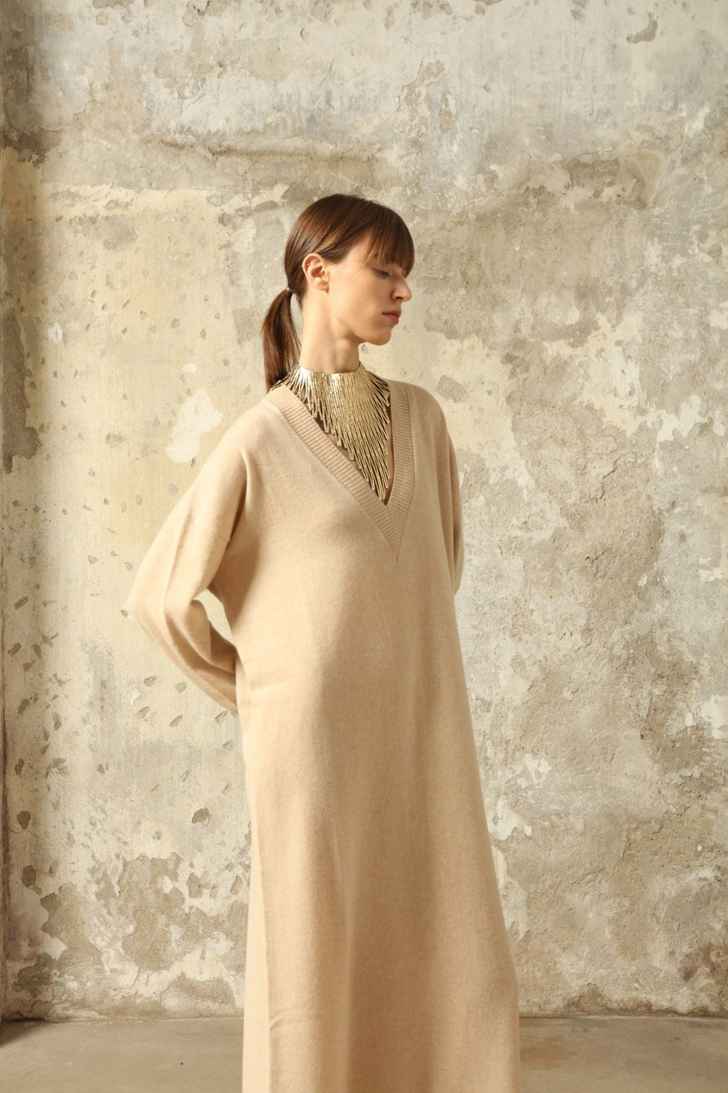 Model is wearing the Natural Katharina V-Neck Cashmere Maxi Dress by House of Nomad Stories, crafted from 100% pure Inner Mongolia cashmere in its uncoloured natural shade, featuring a long flowing silhouette, soft breathable knit, elegant V-neckline, and timeless sustainable luxury design