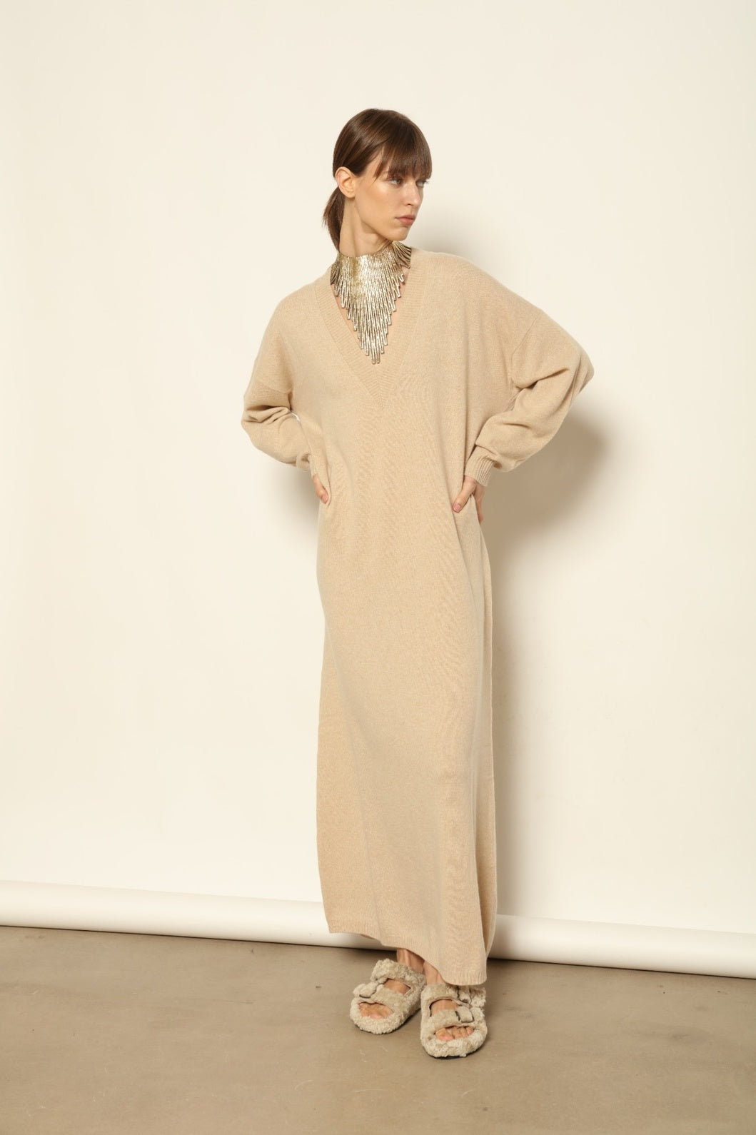 Model is wearing the Natural Katharina V-Neck Cashmere Maxi Dress by House of Nomad Stories, crafted from 100% pure Inner Mongolia cashmere in its uncoloured natural shade, featuring a long flowing silhouette, soft breathable knit, elegant V-neckline, and timeless sustainable luxury design