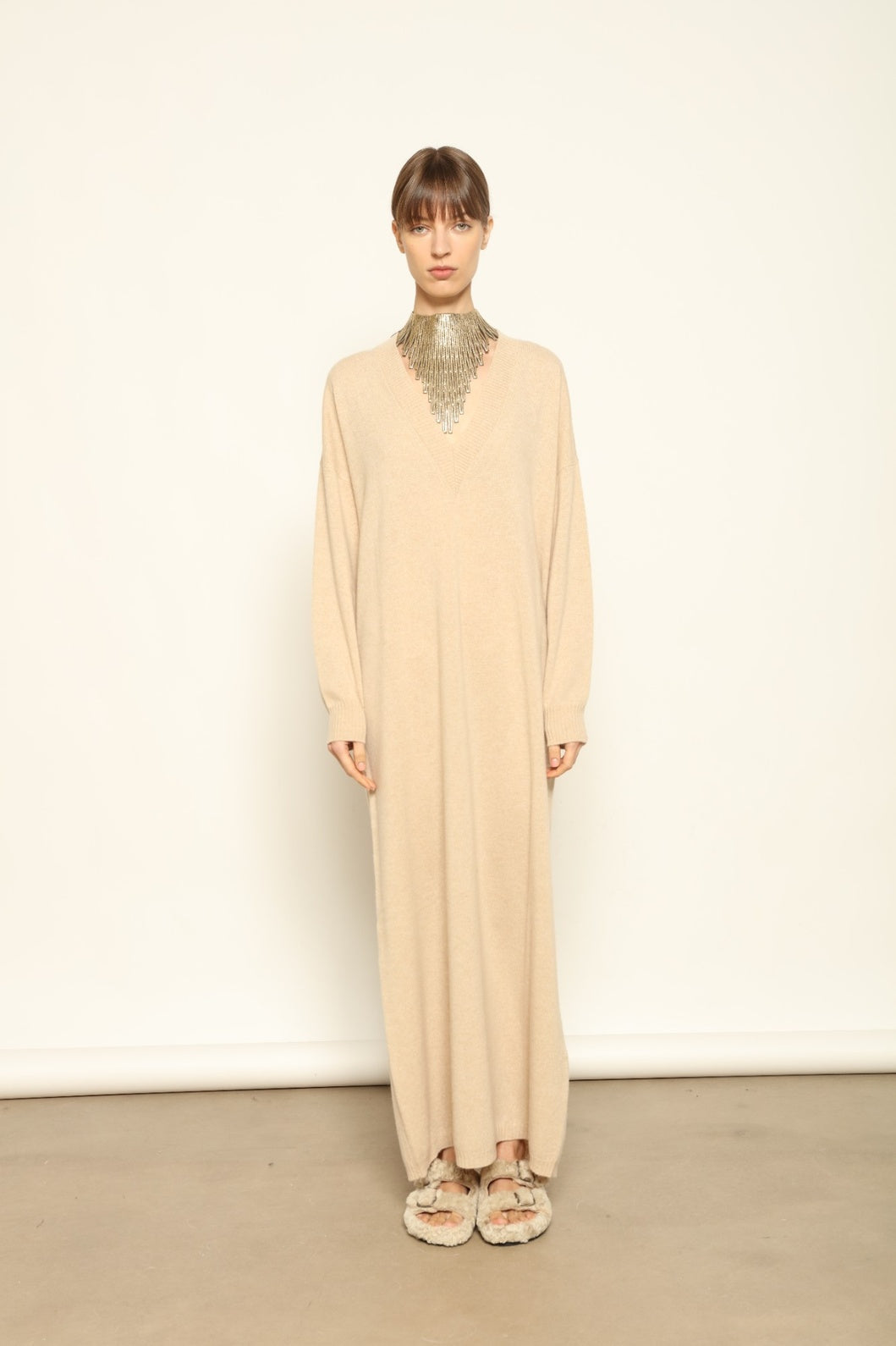 Model is wearing the Natural Katharina V-Neck Cashmere Maxi Dress by House of Nomad Stories, crafted from 100% pure Inner Mongolia cashmere in its uncoloured natural shade, featuring a long flowing silhouette, soft breathable knit, elegant V-neckline, and timeless sustainable luxury design