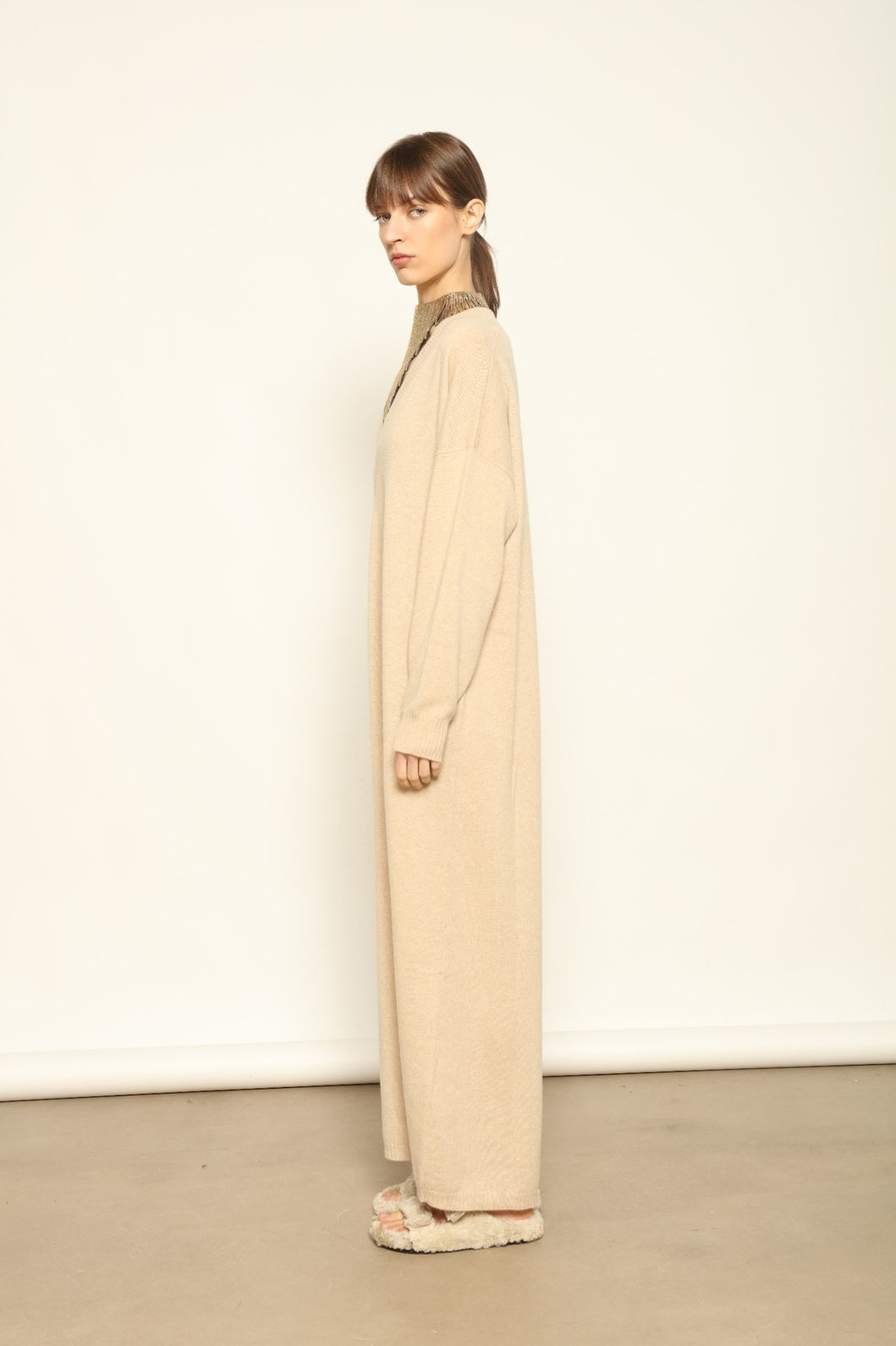 Model is wearing the Natural Katharina V-Neck Cashmere Maxi Dress by House of Nomad Stories, crafted from 100% pure Inner Mongolia cashmere in its uncoloured natural shade, featuring a long flowing silhouette, soft breathable knit, elegant V-neckline, and timeless sustainable luxury design