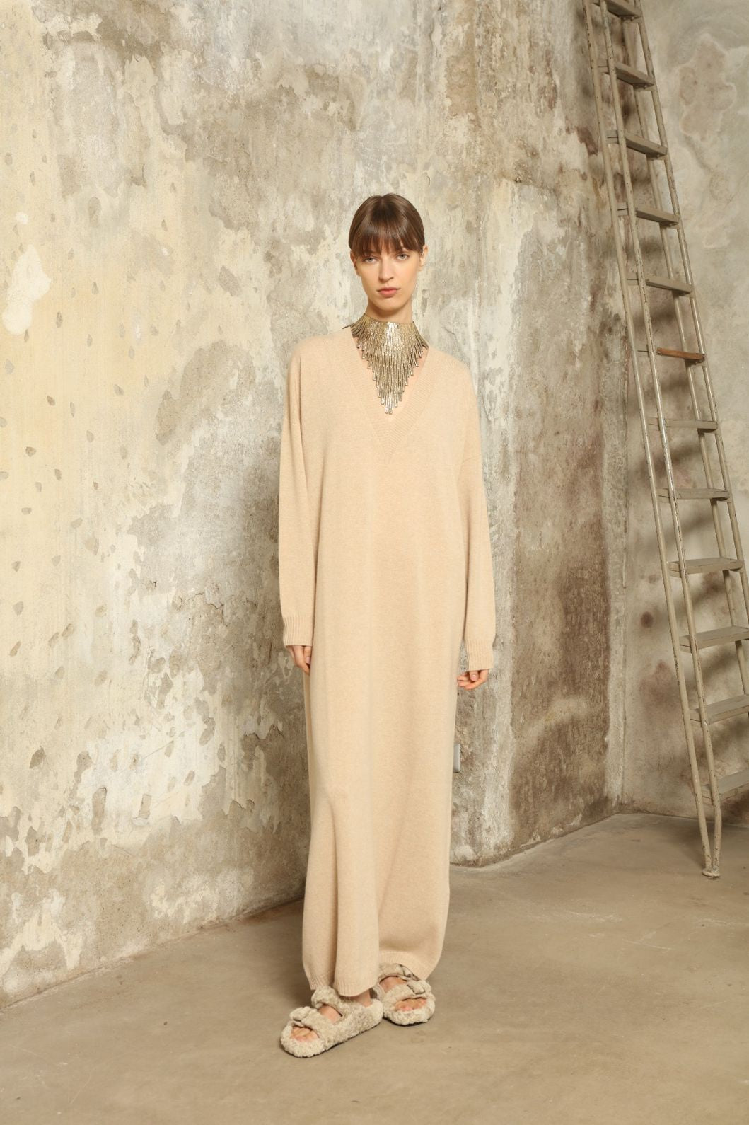 Model is wearing the Natural Katharina V-Neck Cashmere Maxi Dress by House of Nomad Stories, crafted from 100% pure Inner Mongolia cashmere in its uncoloured natural shade, featuring a long flowing silhouette, soft breathable knit, elegant V-neckline, and timeless sustainable luxury design
