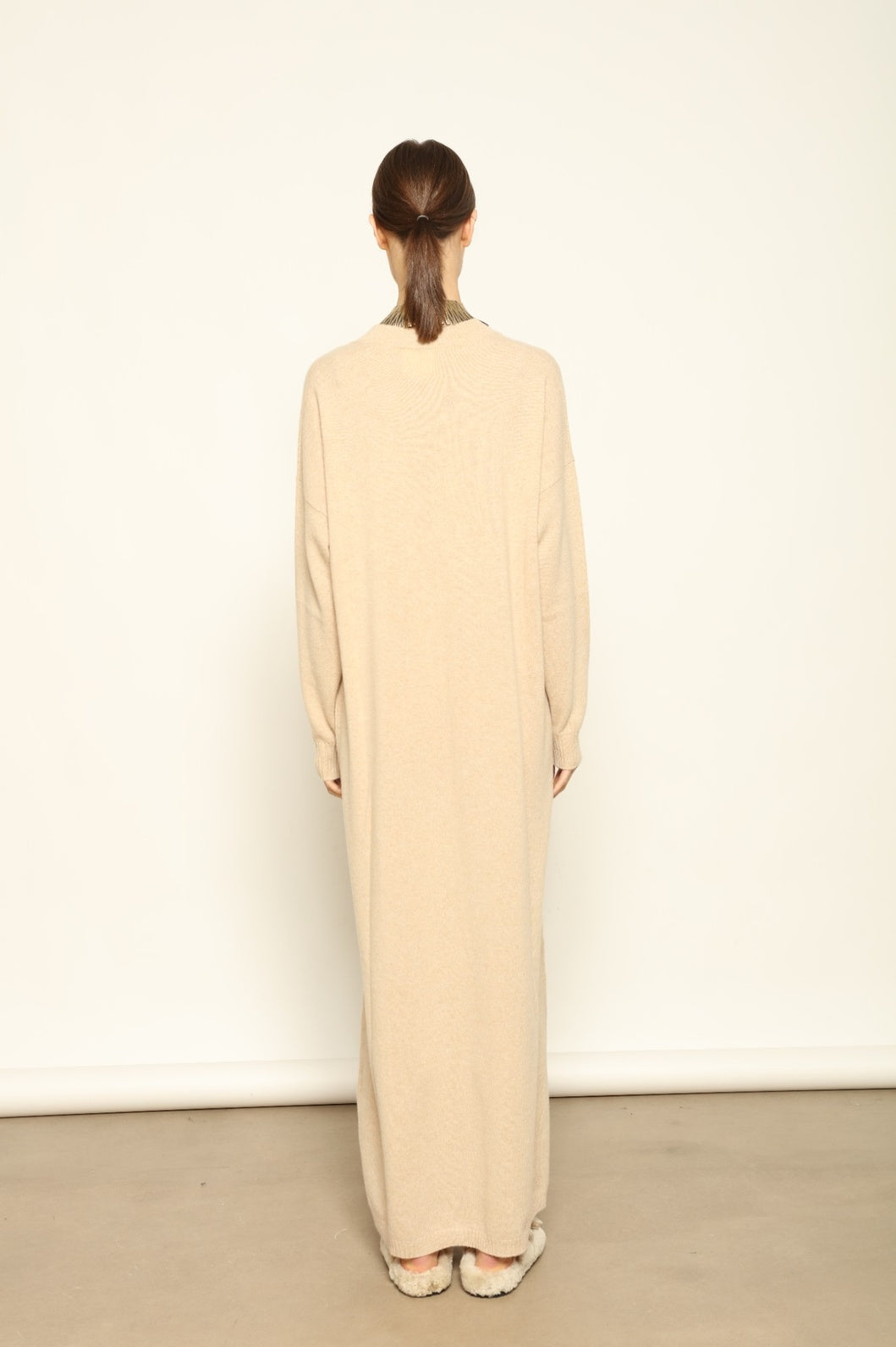 Model is wearing the Natural Katharina V-Neck Cashmere Maxi Dress by House of Nomad Stories, crafted from 100% pure Inner Mongolia cashmere in its uncoloured natural shade, featuring a long flowing silhouette, soft breathable knit, elegant V-neckline, and timeless sustainable luxury design