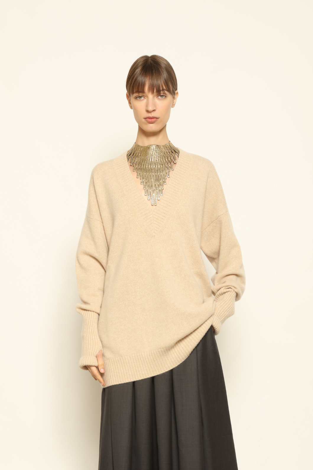 Model is wearing the Natural Nina V-Neck Long Sweater by House of Woven Stories, made from 100% pure undyed Inner Mongolia cashmere, featuring an elongated silhouette, deep V-neckline, soft breathable knit texture, and sustainable Italian craftsmanship