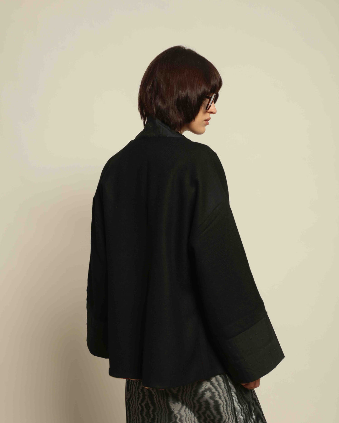 The model is wearing the Obidi Midnight Kantha Jacket in pure black, made of wool with a silk collar and Kantha silk lining, a timeless and versatile piece.