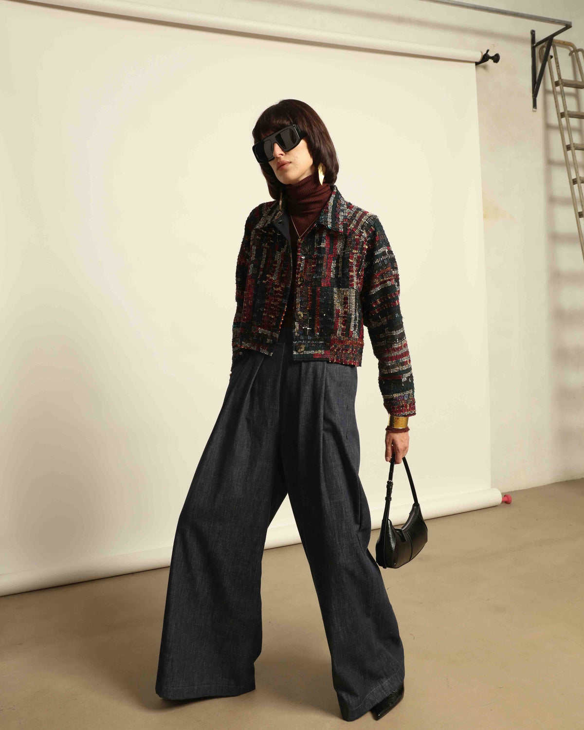 Model is wearing the Denim Parigi Wide-Leg Trousers by House of Nomad Stories, featuring a rich dark denim finish, mid-rise elasticated waist, front pleats, and a relaxed wide-leg silhouette.
