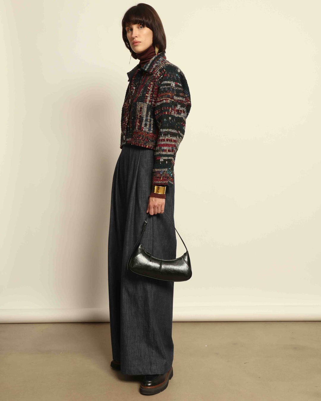 Model is wearing the Denim Parigi Wide-Leg Trousers by House of Nomad Stories, featuring a rich dark denim finish, mid-rise elasticated waist, front pleats, and a relaxed wide-leg silhouette.

