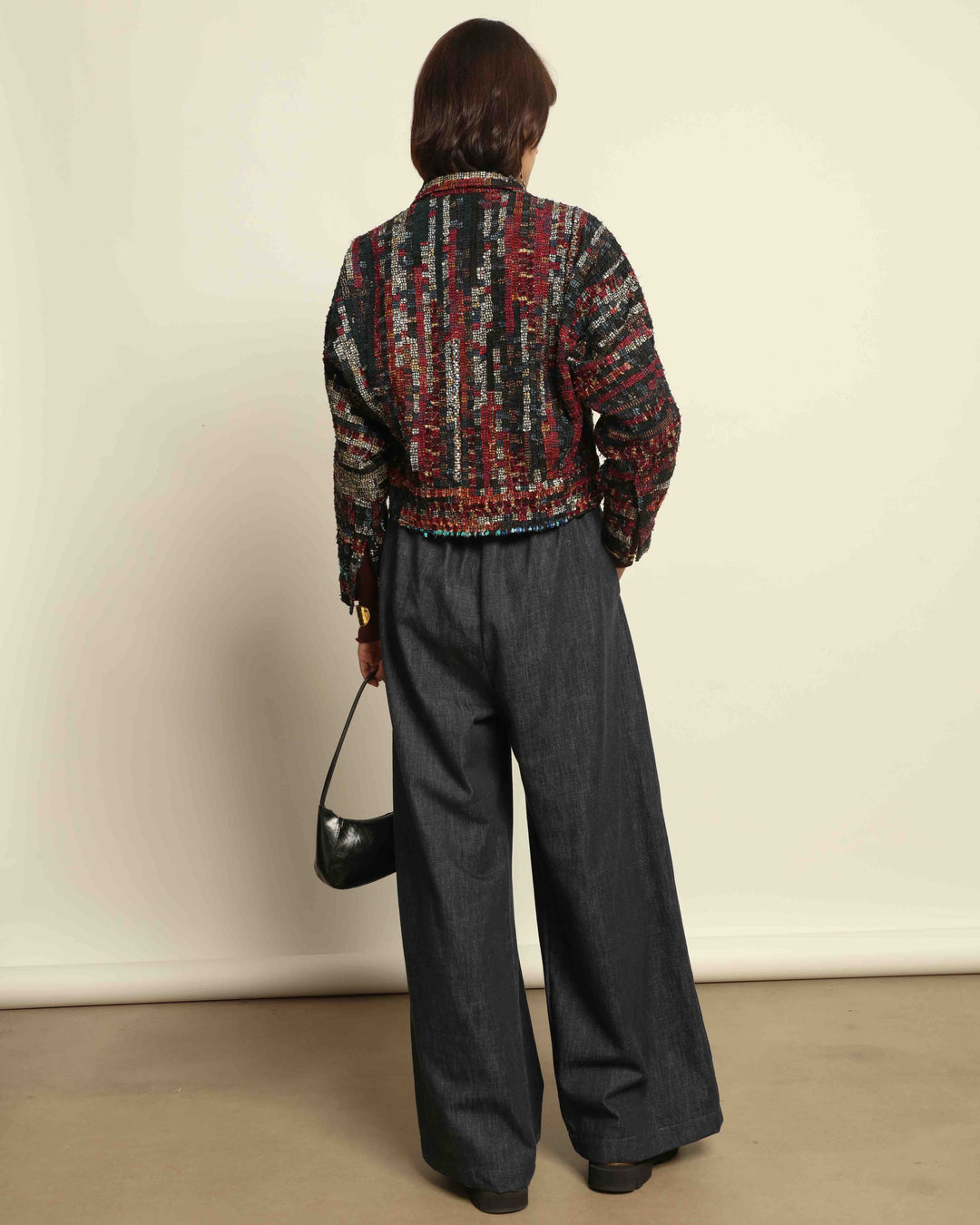 Model is wearing the Denim Parigi Wide-Leg Trousers by House of Nomad Stories, featuring a rich dark denim finish, mid-rise elasticated waist, front pleats, and a relaxed wide-leg silhouette.
