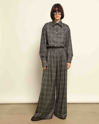 Model is wearing the Parigi Grey Check Trousers by House of Nomad Stories, featuring a refined grey check pattern and a tailored silhouette, handcrafted in Piedmont, Italy.