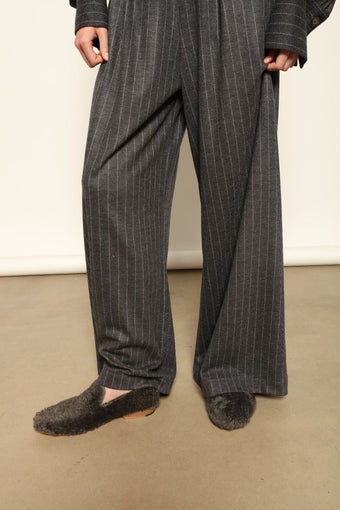 Model wearing Parigi Trousers in Double Jersey Striped Grey and White by House of Woven Stories, part of the curated selection, made in Italy from 100% Merino wool, featuring soft double jersey texture and elegant striped design for refined comfort and timeless style.
